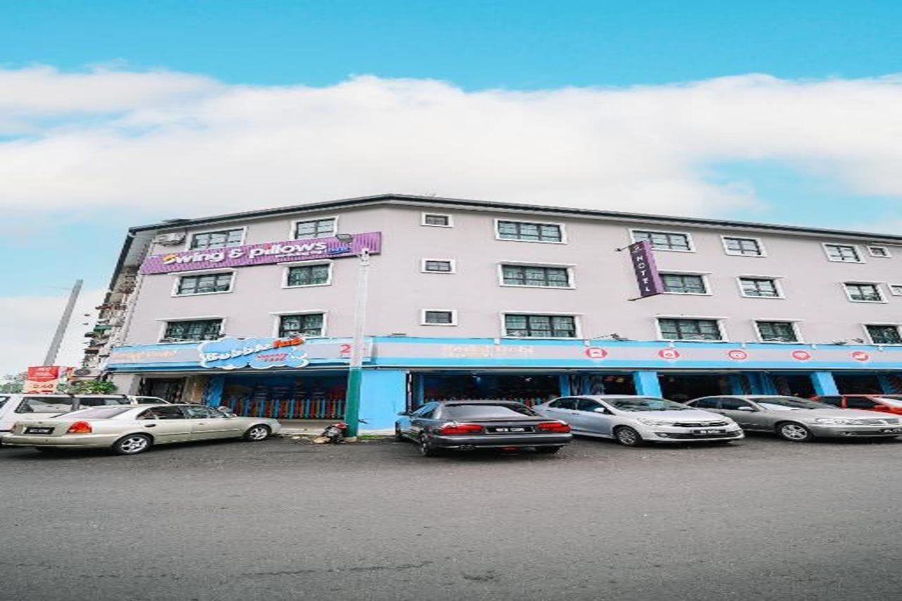 A hotel with multiple floors, a parking lot with several cars, and a clear sky.