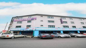 A hotel with multiple floors, a parking lot with several cars, and a clear sky.