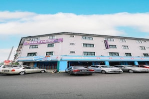 Un hôtel à étages, un parking avec plusieurs voitures et un ciel dégagé.
