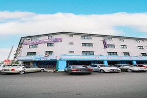 Un hotel de varios pisos, un estacionamiento con varios coches y un cielo despejado.