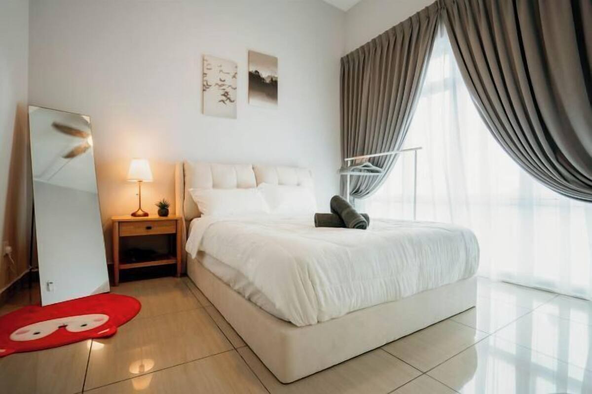 Habitación de hotel moderna con cama, mesitas de noche, lámpara, espejo y una obra de arte en la pared.