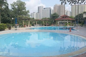 A swimming pool with lounge chairs and a gazebo, surrounded by greenery and high-rise buildings in the background. - Mount Austin Muji Style 4 pax Deluxe Room (Tebrau)