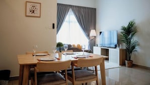 Comedor con una mesa dispuesta para cuatro, un sofá al fondo y un televisor sobre un mueble.