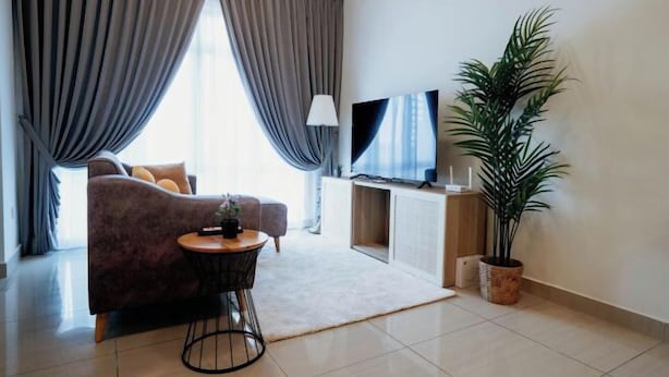 Una sala de estar moderna con un sofá, un televisor, una mesita y una planta en maceta.