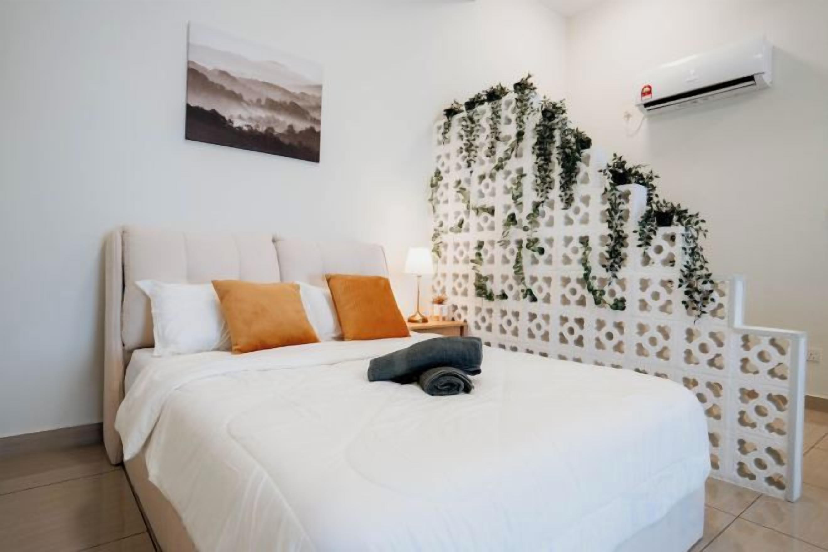 Un dormitorio con cama, almohadas, una mesita de noche y un equipo de aire acondicionado.