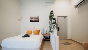 Una habitación de hotel con una cama, una mesita de noche, una lámpara, una puerta y una planta en la pared.