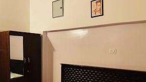 Une chambre à coucher avec un lit, une armoire, un miroir et un mur orné d’un cadre de tableau.