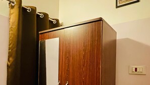 Une armoire en bois avec un miroir, un rideau et un tableau encadré accroché au mur.
