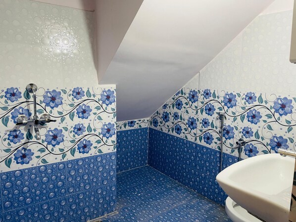 A bathroom with blue floral tiles, a white sink, and a shower with a chrome faucet. - Zivo Stays Guest House Rethibowli (Hyderabad)