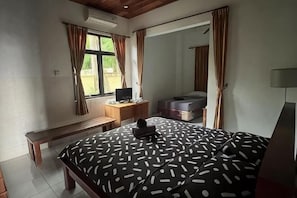 A bedroom with a bed, a desk, a chair, a bench, a window, and a mirror. - Jasri Ombak (Bali)