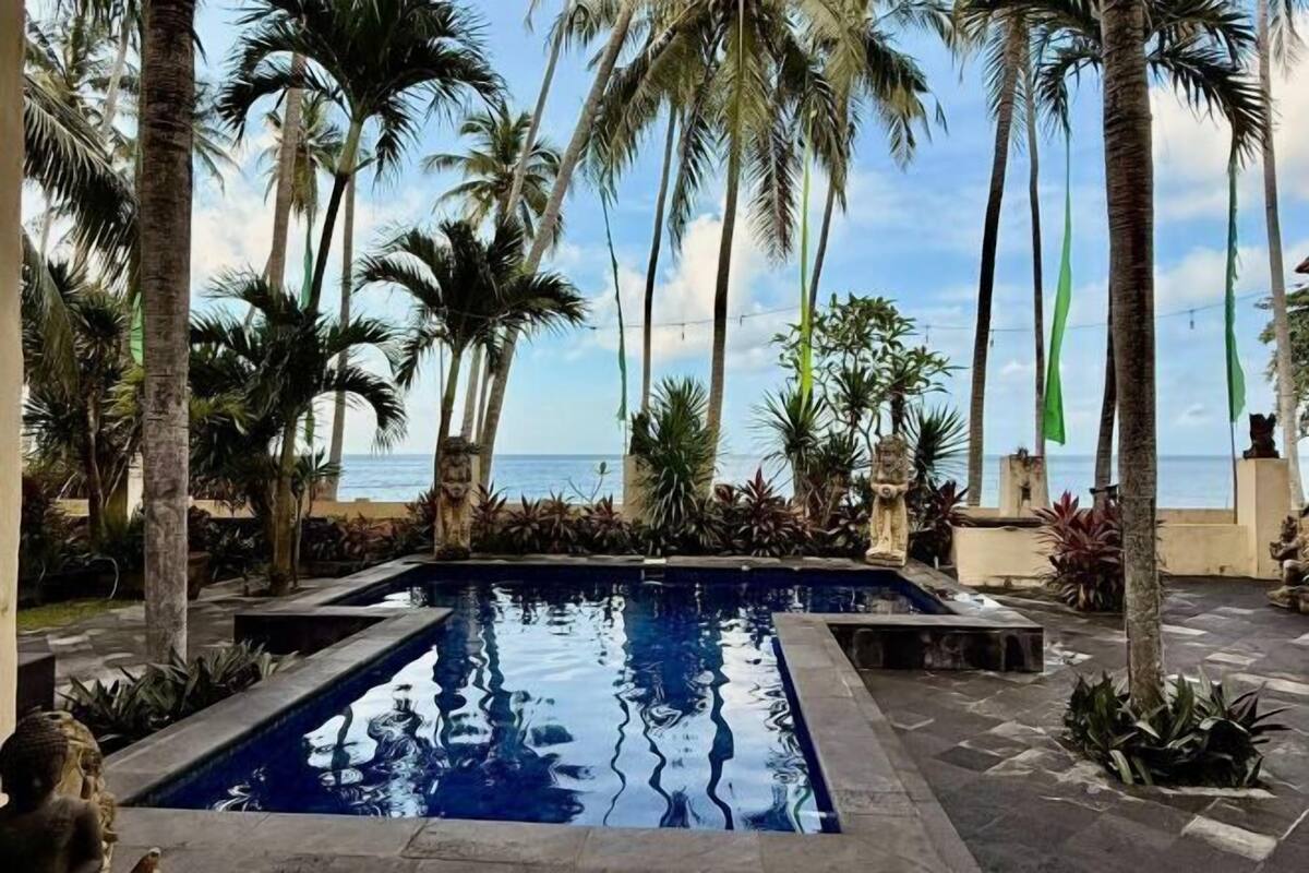 Zona de piscina con palmeras y vista al océano.