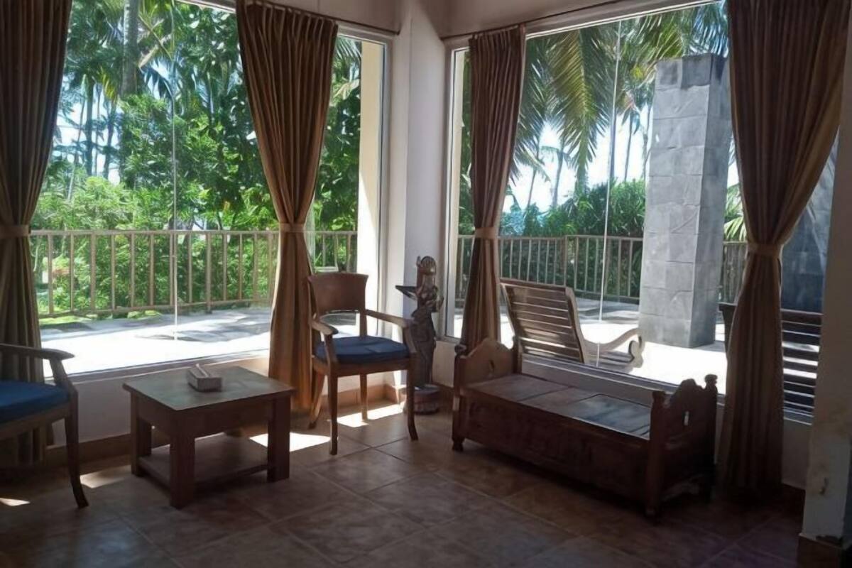 Un balcón con vistas a palmeras, un banco de madera y una mesa con sillas.