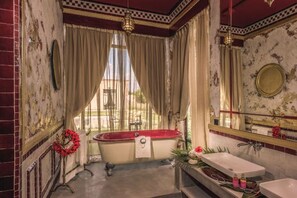 A bathroom with a red clawfoot bathtub, a white sink, and a large mirror. - The Source Hotel Music & Spa (Marrakech)
