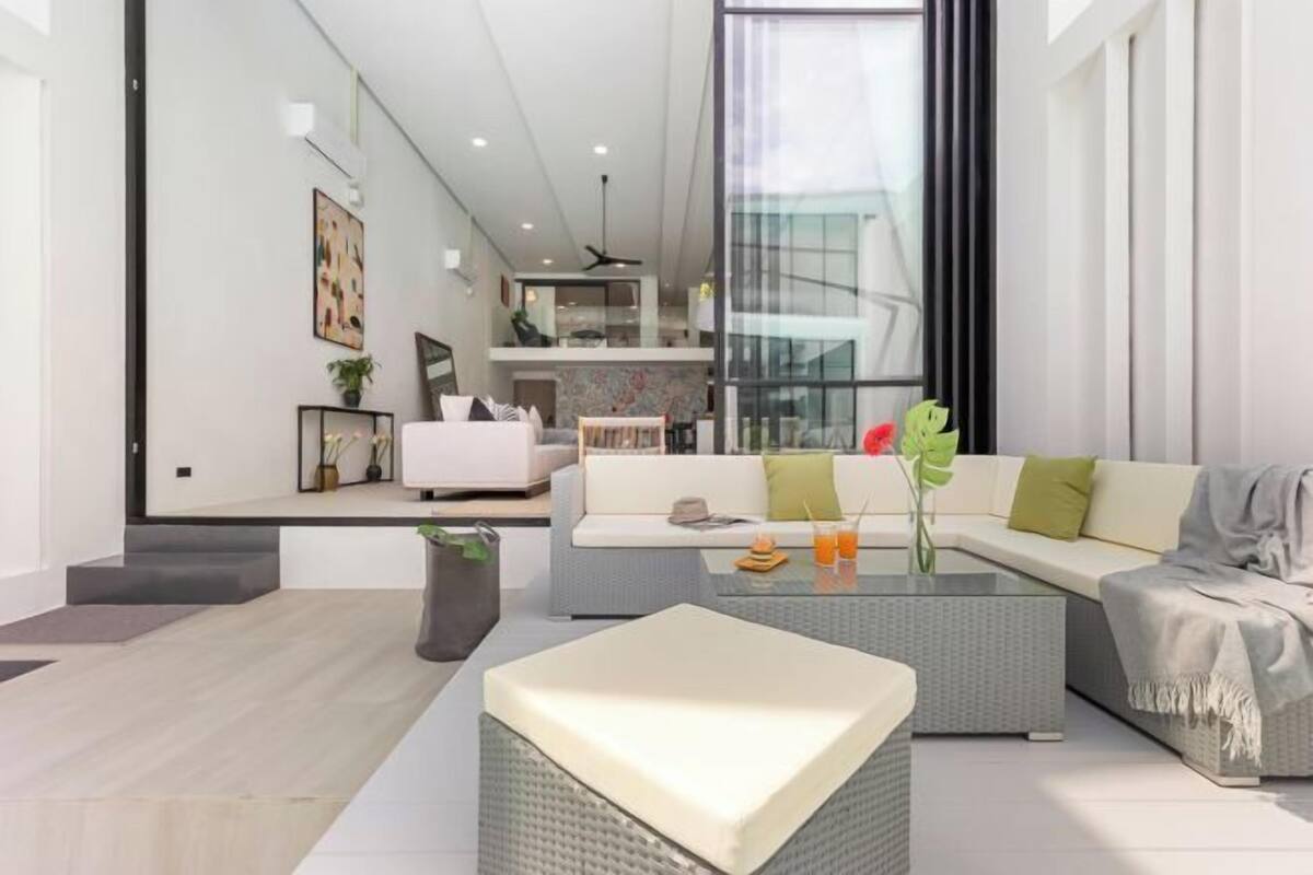 A modern living room with a sofa, coffee table, and a view of a kitchen and dining area.