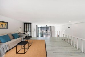 Una sala de estar moderna con sofá, mesa de centro y vistas a un balcón.