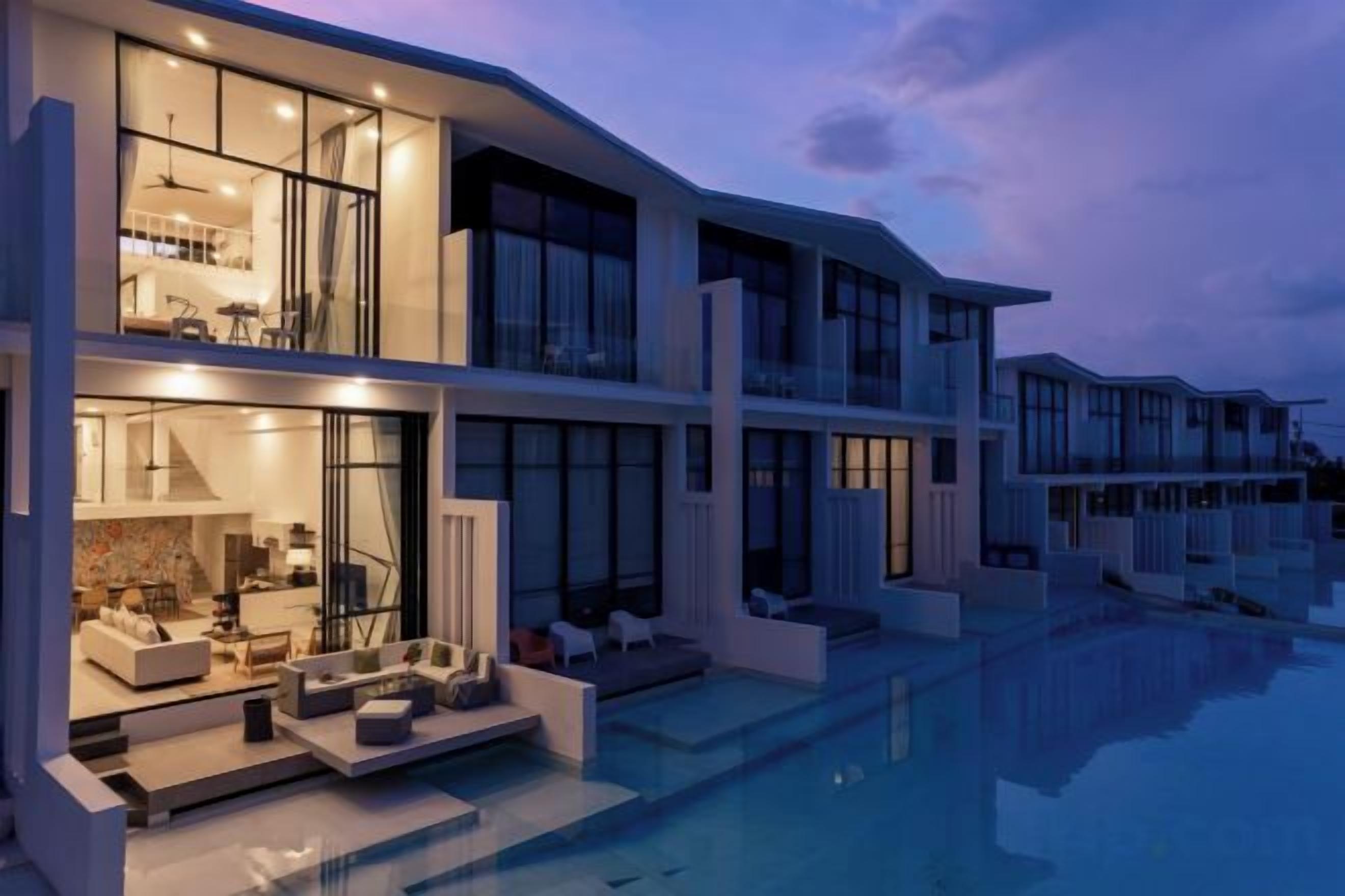A modern multi-story house with a swimming pool, large windows, and outdoor seating.