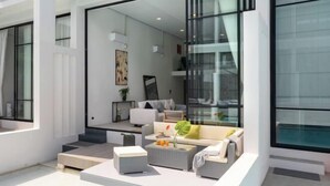 A modern living room with a sofa, coffee table, and a glass door leading to a balcony.