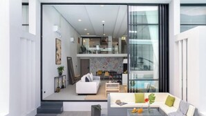A modern living room with a sofa, coffee table, and a view into the kitchen.