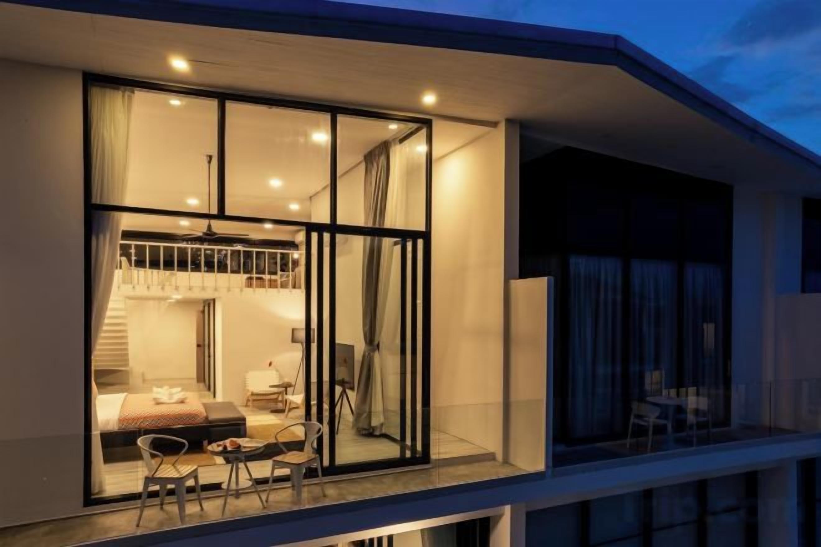 Un edificio moderno con un balcón, ventanas amplias y una escalera que conduce a un nivel superior.