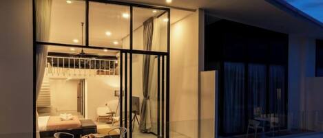 Un edificio moderno con un balcón, ventanas amplias y una escalera que conduce a un nivel superior.