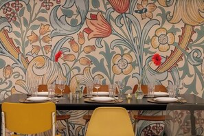 A dining table set with plates, glasses, and cutlery, surrounded by chairs.