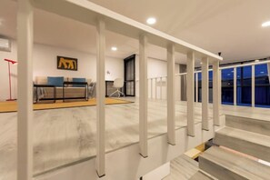 Un intérieur moderne avec un escalier, un ensemble de canapés et une œuvre d’art accrochée au mur.
