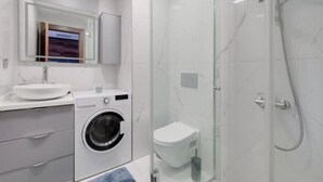 Un bagno moderno con doccia vetro-ceramica, lavatrice e WC.