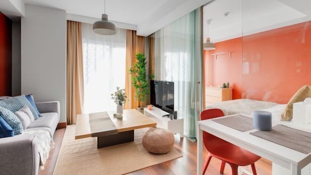 Camera d'albergo moderna con divano, tavolo da pranzo e letto con parete decorata in rosso.