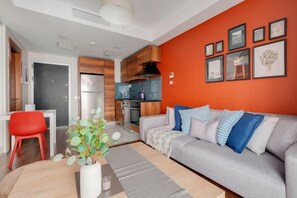 A modern living room with a grey sofa, red chair, and a dining area with a white table and red chair. - Luxury Residence 5 Min to Metro in Sisli, Bomonti (Istanbul)