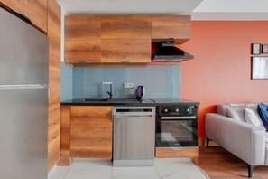 A compact kitchen with wooden cabinetry, a dishwasher, an oven, and a modern countertop. - Luxury Residence 5 Min to Metro in Sisli, Bomonti (Istanbul)