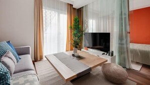 Un soggiorno moderno con un divano, un tavolino, una TV e una pianta.