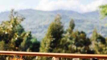 A dining table with food and drinks, overlooking a mountainous landscape.