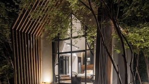 A treehouse with a wooden deck, a glass enclosure, and a bed visible inside. - Payana Kampot (Makprang)