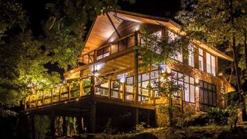 Uma cabana de madeira com varanda, rodeada por árvores.