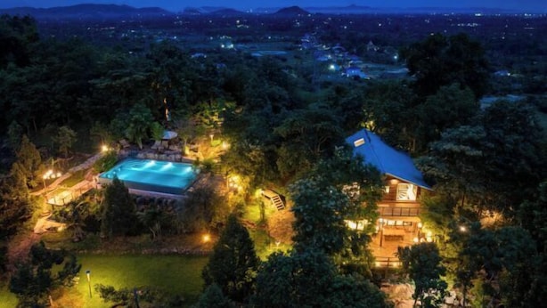A large house surrounded by dense trees, with a swimming pool and a well-lit patio area. - Payana Kampot (Makprang)