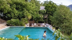 A rectangular swimming pool with clear blue water, surrounded by lush greenery and trees. - Payana Kampot (Makprang)