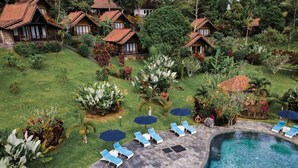 Un resort con varias edificaciones tipo bungalow, una piscina y un jardín bien cuidado.