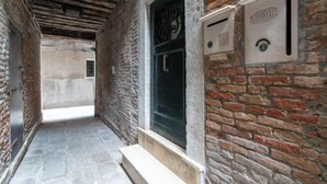 A narrow corridor with stone flooring, a wooden bench, and a door with a metal handle. - Rooftop Terrace Penthouse & 360° Views Venice5th (Venice)