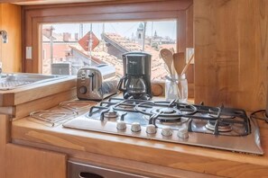 Een keuken met een gasfornuis, broodrooster, koffiezetapparaat en keukengerei.