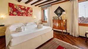 A hotel room with a bed, wooden beams, a painting, a cabinet, and a window with curtains. - Rooftop Terrace Penthouse & 360° Views Venice5th (Venice)