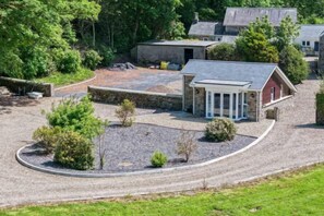 A building with a covered porch, a gravel driveway, and a stone wall. - The Pig STY - 1 Bedroom Studio - Princes Gate (Narberth)
