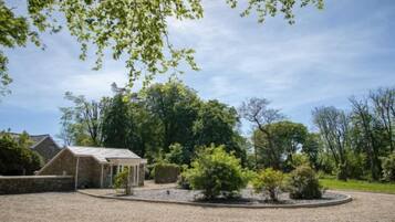 A building with a gravel driveway, surrounded by trees and a clear sky.