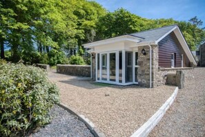 A small, single-story building with a sloped roof, a stone foundation, and a gravel driveway. - The Pig STY - 1 Bedroom Studio - Princes Gate (Narberth)