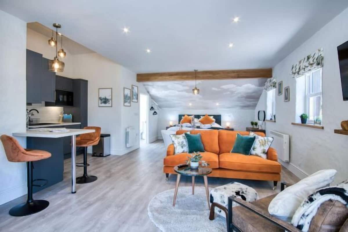 A modern living room with a sofa, coffee table, and a kitchen area with bar stools.