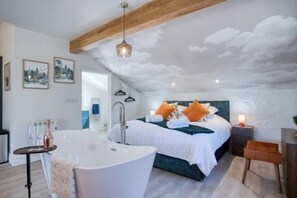 A bedroom with a large bed, a bathtub, and a wooden ceiling. - The Pig STY - 1 Bedroom Studio - Princes Gate (Narberth)