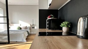 Et moderne soveværelse med seng, natbord og et lille tekøkken med mikrobølgeovn og elkedel.