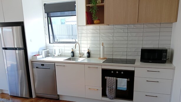 Una cocina moderna con electrodomésticos de acero inoxidable, armarios blancos y salpicadero de azulejos.
