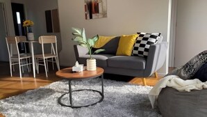 Una sala de estar moderna con un sofá gris, una mesa de centro redonda y un comedor con sillas y una mesa.