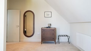 Une chambre à coucher avec une commode, un miroir, un radiateur et un tableau encadré au mur.