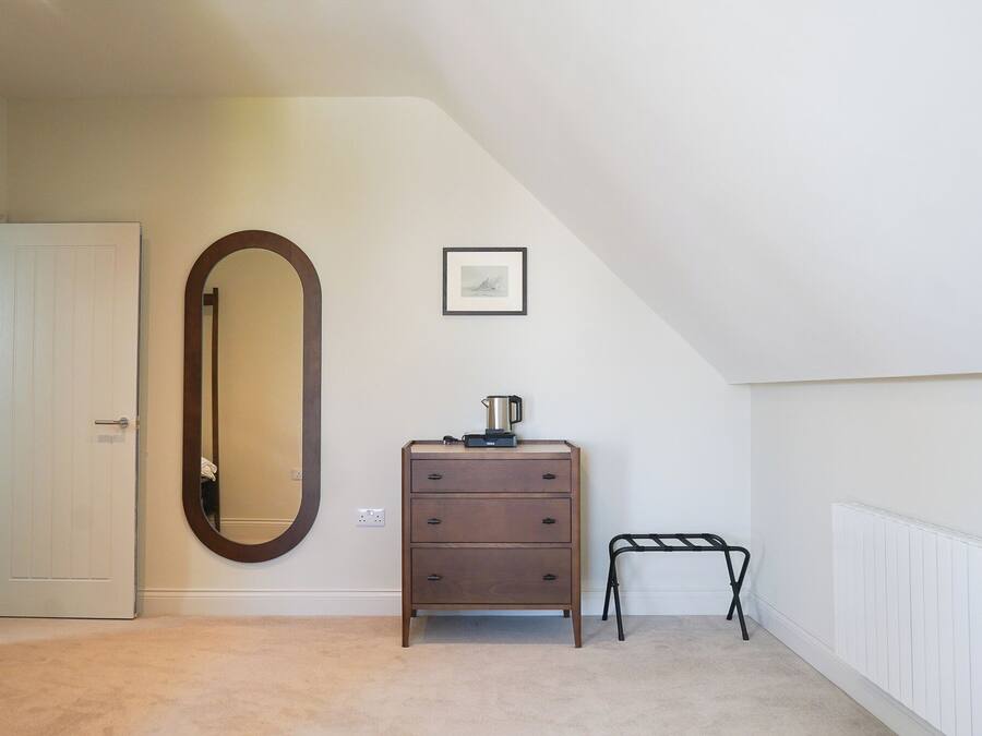 A bedroom with a dresser, a mirror, a radiator, and a framed picture on the wall.